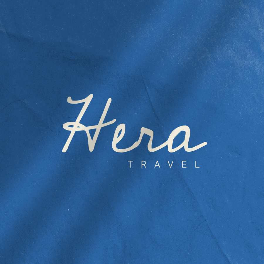 Hera Travel logo: cream handwritten script on textured Mediterranean blue.